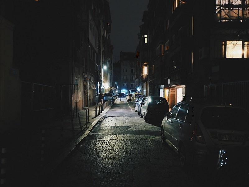 A street late at night with parked cars and shops