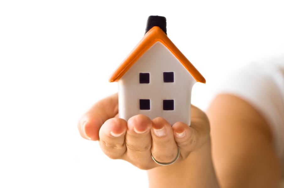 A small toy house on a human hand