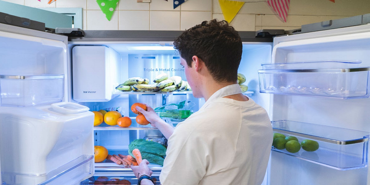 A man arranging food in a fridge