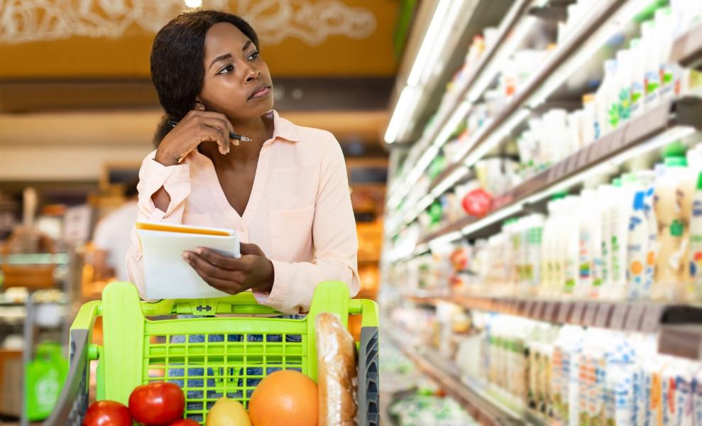 Unhappy African American Woman Holding Grocery Shopping List In Supermarket