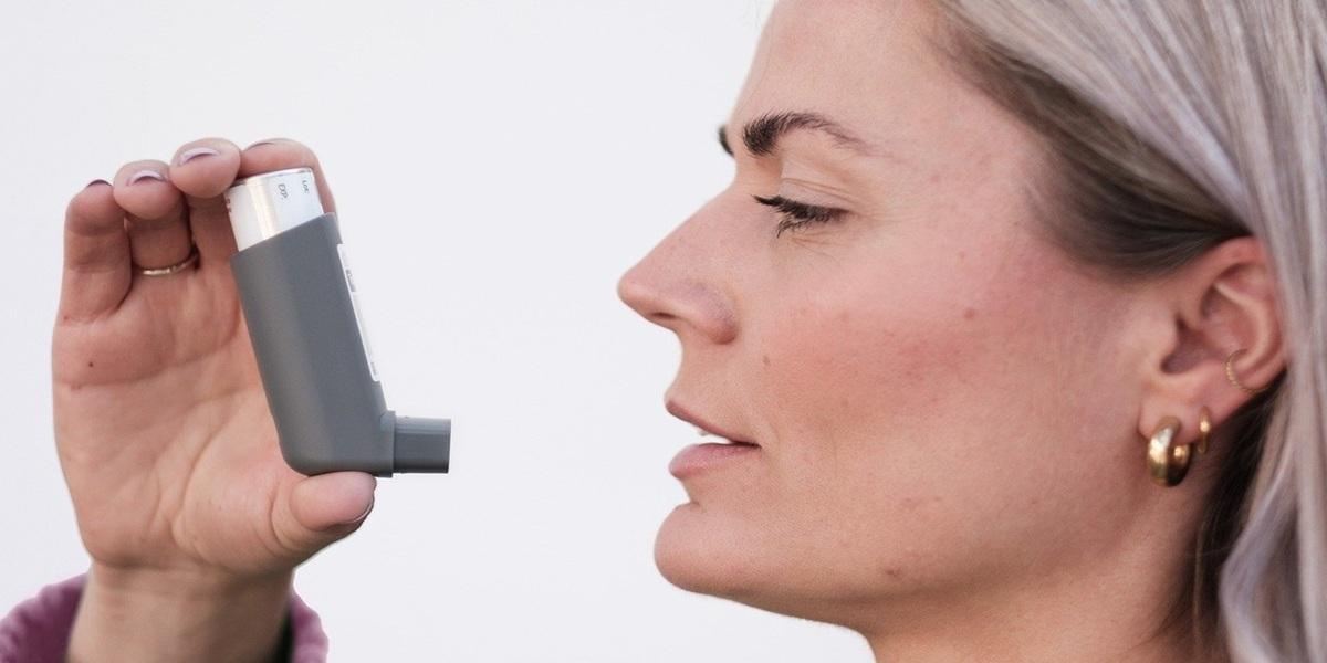 A lady taking her inhaler medication for asthma.