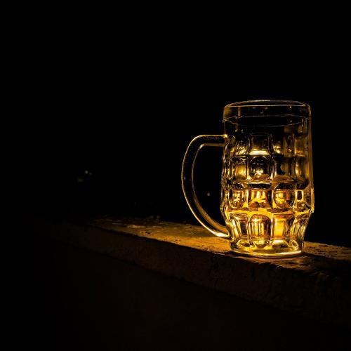 A pint of beer sat on a bar with a black background