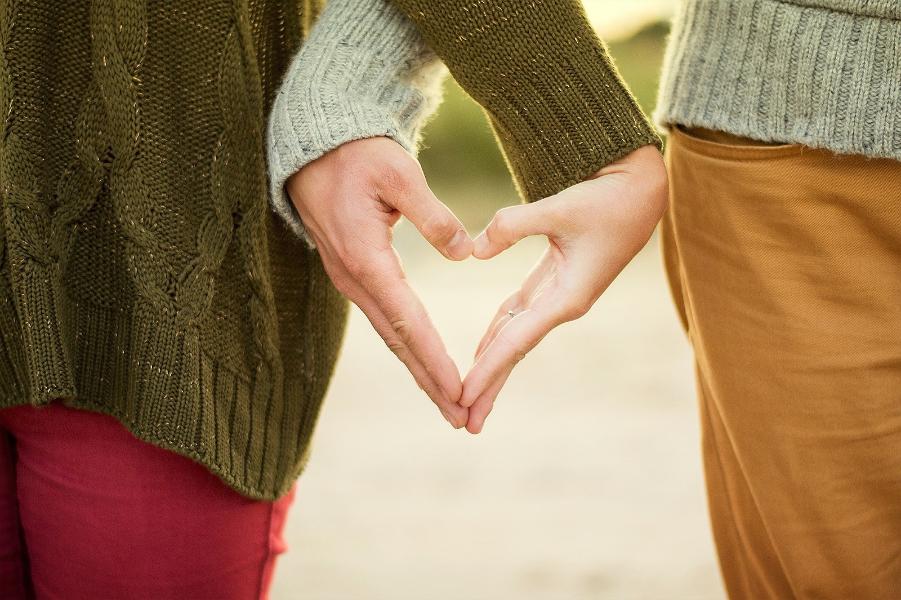 A couple creating a heart shape with there hands