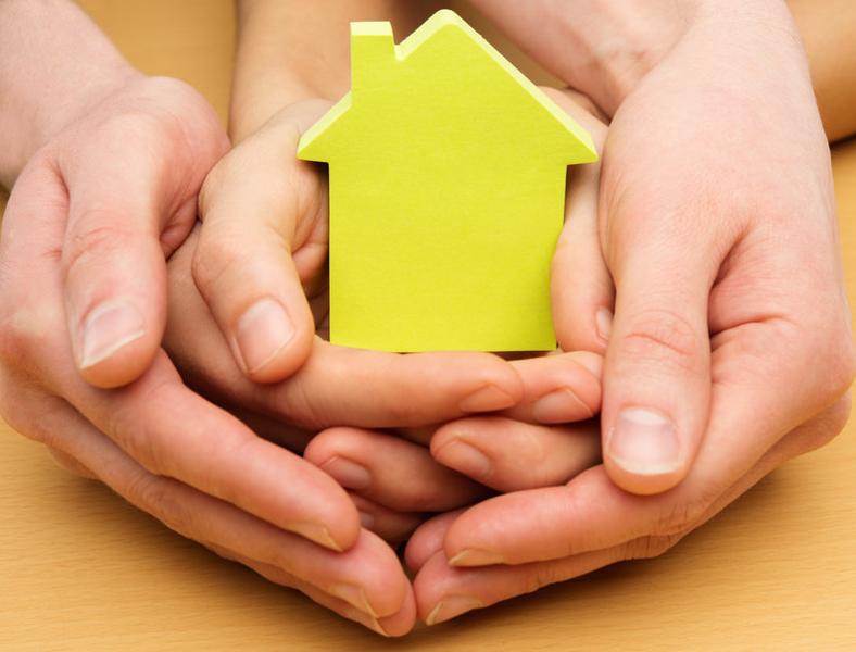 Man and woman hands holding conceptual paper house