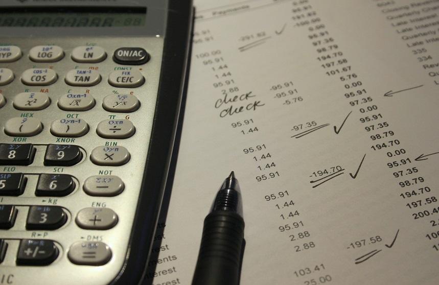 A calculator with a sheet of paper with numbers on it and a pen