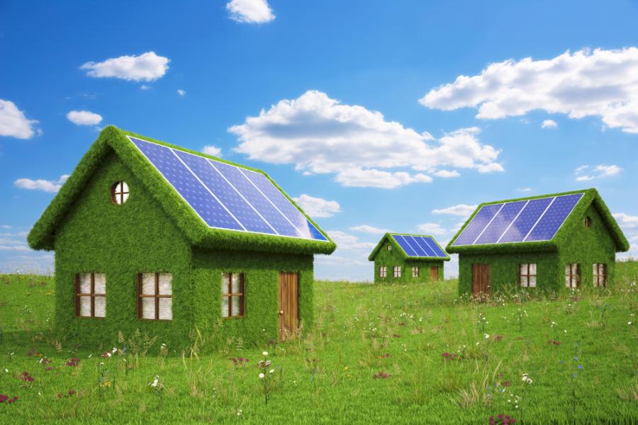 Three houses made out of grass and wood with solar panels on the rough - shutterstock_105757901